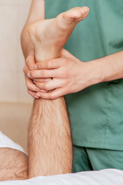 Primo piano del piede dell'uomo in mano del massaggiatore durante la procedura di salute
. - Foto, immagini