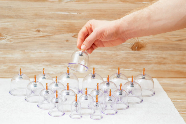Hand van massager met vacuüm glazen beker over set potten op de tafel in spa. - Foto, afbeelding