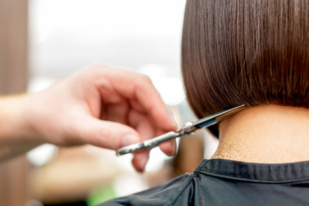 Rückansicht des Friseurs Hand schneidet kurze Haare der Frau im Friseurstudio. - Foto, Bild