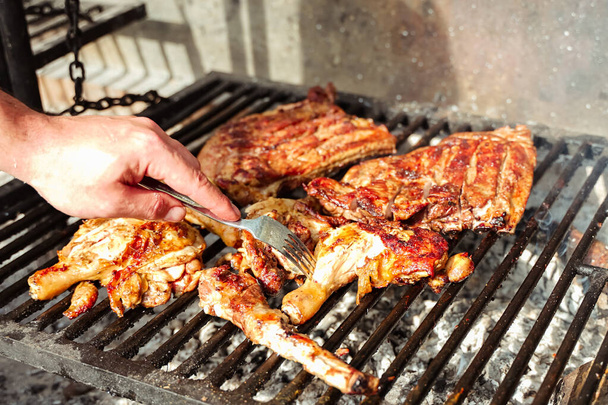 Szabadidő, élelmiszer, emberek és nyaralás koncepció - férfi főzés hús barbecue grill, nyári szabadtéri - Fotó, kép