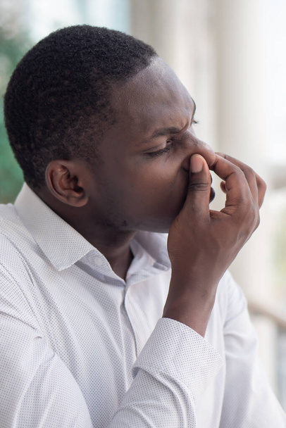African black man covering his nose for bad smell; African black man plugging his nose to display concept of bad smell, bad breath, dirty or filthy thing, rotten stuff, gross fart smell - Foto, afbeelding