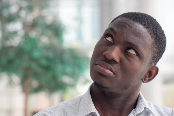 Hombre negro africano molesto mirando hacia arriba; hombre negro africano mirando con sentimiento negativo, mala emoción, estrés, problema
 - Foto, imagen