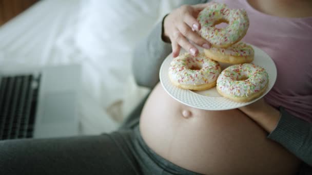 Guarda il video di donna incinta allegra mangiare ciambelle. Girato con telecamera ad elio rosso in 8K
   - Filmati, video