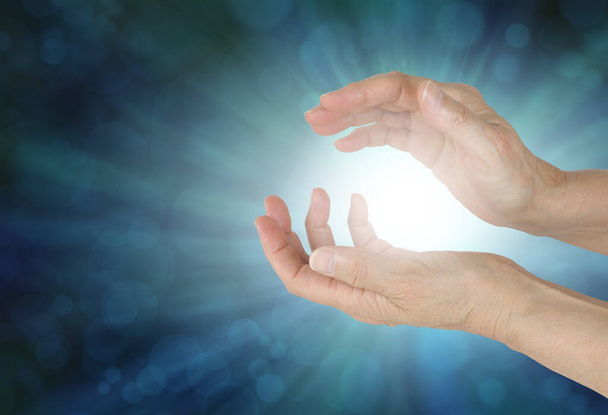 Mains féminines détectant le champ énergétique quantique - mains féminines taillées autour d'une lumière blanche sur un fond de vignette vert rayonnant avec espace de copie - Photo, image