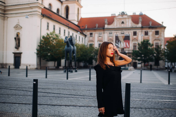 A young beautiful stylish girl in a black summer dress with heels walks in the city.Girl model in the Czech Republic. BRNO. - Фото, зображення