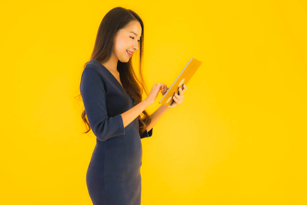 Sarı izole arka planda akıllı tabletli güzel Asyalı kadın portresi. - Fotoğraf, Görsel