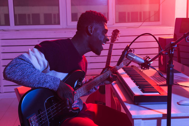 Africký profesionální hudebník nahrávající baskytaru v digitálním studiu doma, koncept hudební produkce. - Fotografie, Obrázek