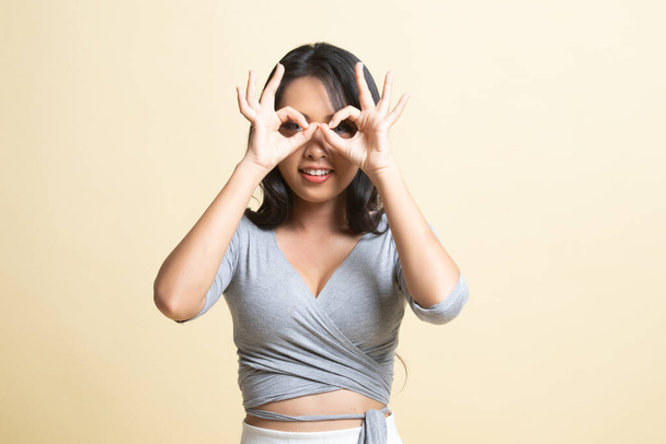 Asian woman do funny  double OK sign as glasses   on beige background - 写真・画像