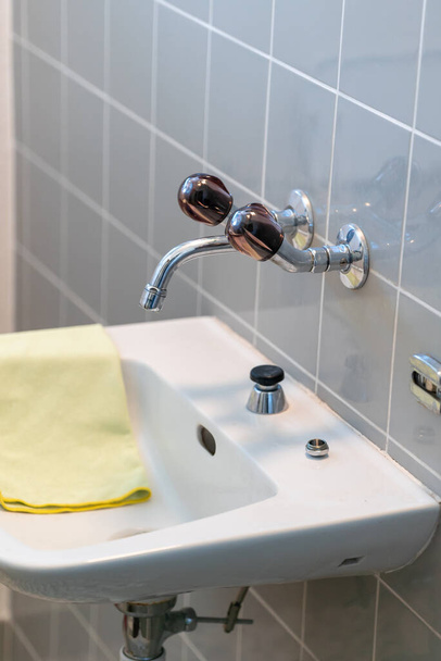 yksinkertainen vanha kaakeloitu kylpyhuone ja pesuallas eri siivoustarvikkeet
 - Valokuva, kuva