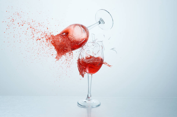 Red wine glasses flying, colliding and crushing on white background. Splashes. Broken glass. High speed photography of liquids - Photo, Image