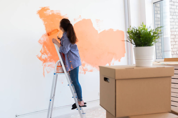 Repair in the apartment. Happy woman paints the wall with paint. - 写真・画像