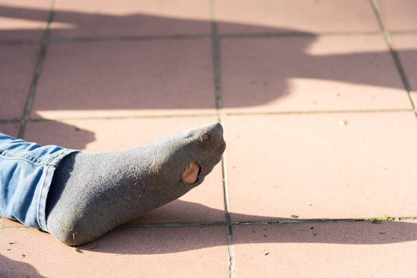 Chlapecká noha s džínama a starou ponožkou s dírou venku - Fotografie, Obrázek