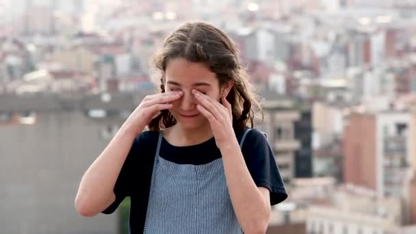 Dziewczynka pocierająca swoimi irytującymi oczami ulicę miasta - Materiał filmowy, wideo