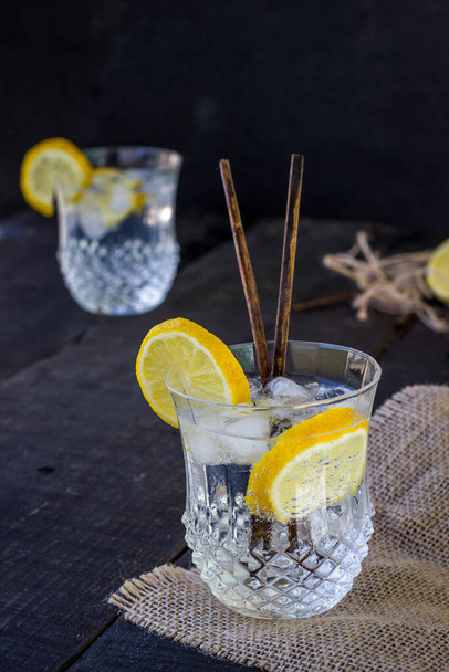 Gin et verre tonique avec coin citron sur table noire. vue sur le zénith. focus sélectif
 - Photo, image