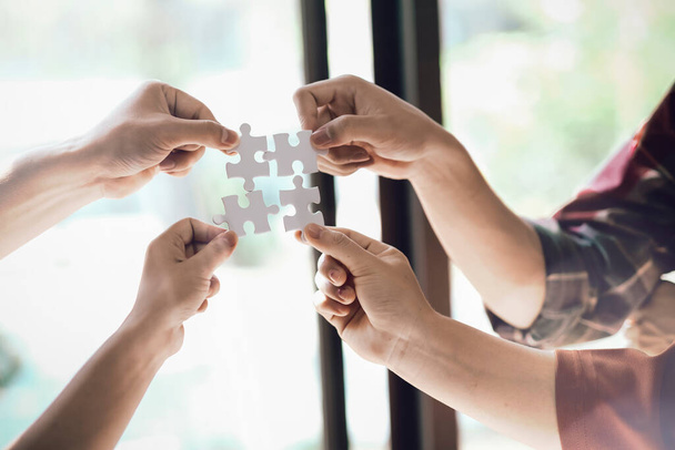 Closeup hand of business people connecting jigsaw puzzle with sunlight effect, Business solutions and represent team support and help concept, success and strategy concep - Photo, Image