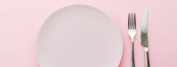 Prázdný talíř a příbory jako maketa set na růžovém pozadí, horní stolní nádobí pro šéfkuchaře stolní dekorace a značkování menu - Fotografie, Obrázek