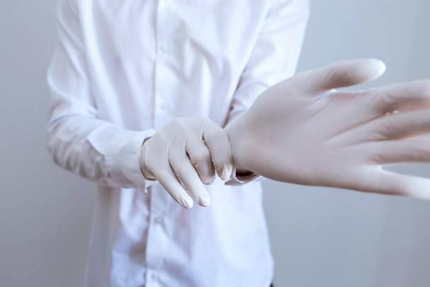man wears white medical gloves on a white background - Foto, afbeelding