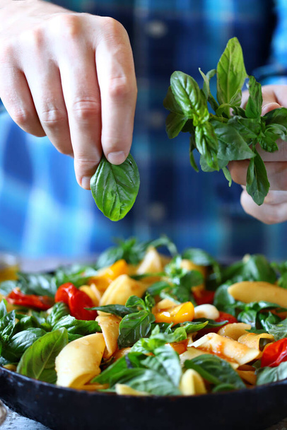Hands of a chef with basil for cooking Italian pasta. Cooking one pan pasta. - Photo, Image