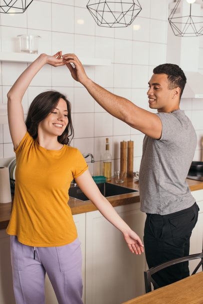 happy interracial couple dancing in kitchen  - Фото, зображення