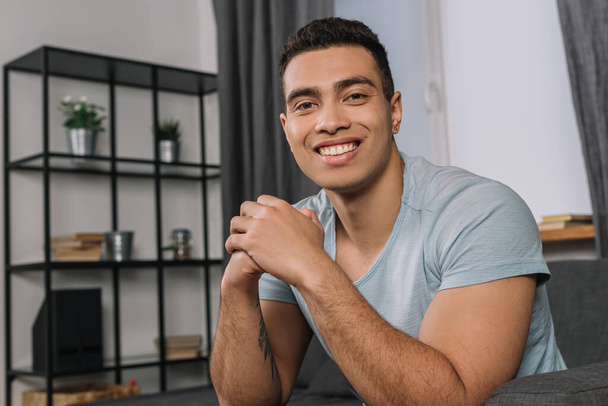 happy mixed race man looking at camera in living room  - Photo, image