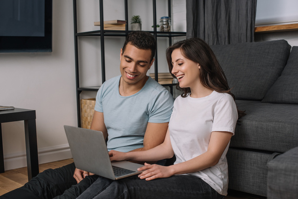 heureux couple interracial en utilisant ordinateur portable à la maison
 - Photo, image
