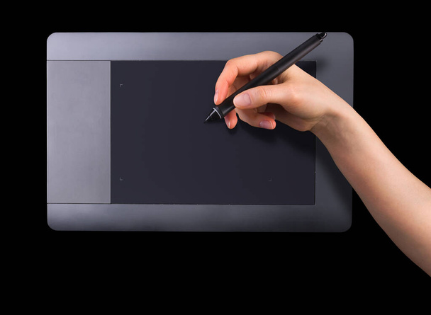 Hand holding digital graphic pen and drawing graphic tablet for illustrators, designers and photographers isolated on black background - Fotó, kép