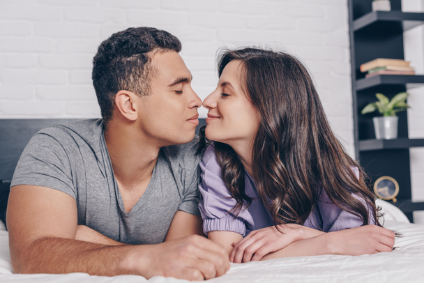 side view of cheerful and young multiracial couple with closed eyes - Photo, image