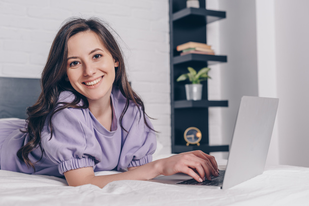 cheerful and attractive freelancer using laptop in bed  - Fotoğraf, Görsel