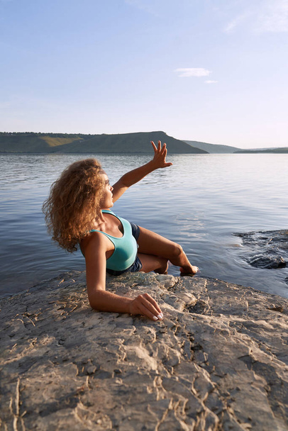 Girl lying on stone on background of mountains and water. - Valokuva, kuva