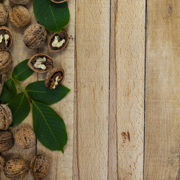 Walnuts and leaves on a wooden table.Border. - Fotó, kép