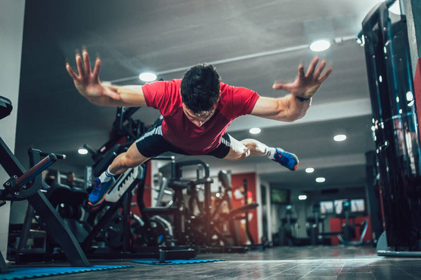Retrato de un hombre de fitness haciendo flexiones extremas en el gimnasio. Enfoque selectivo
. - Foto, Imagen
