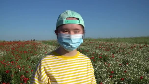 Κορίτσι με μάσκα στο πρόσωπό της στο φόντο στο χωράφι με τα λουλούδια - Πλάνα, βίντεο