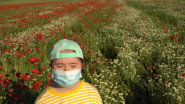 Tyttö naamari kasvoillaan taustalla kukkien alalla - Materiaali, video