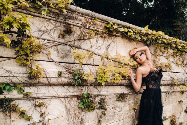 A stylish bride in a black wedding dress poses in the ancient French city of Avignon. Model in a beautiful black dress. Photo shoot in Provence. - Photo, Image