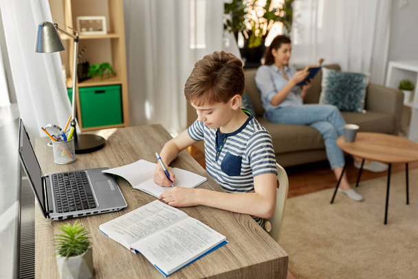 student boy with book writing to notebook at home - Photo, Image