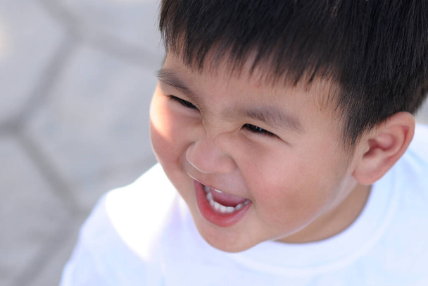 Ένα λευκό αγόρι να γελάει χαρούμενο. - Φωτογραφία, εικόνα