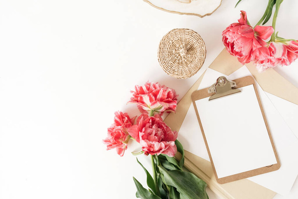 Schránka tablet blok s prázdným listem kopírovat prostor a růžové květy na bílém pozadí. Plochá, šablona shora. Kancelářské prostory pro ženy - Fotografie, Obrázek
