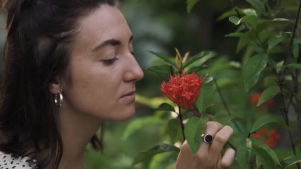庭の若い美しい女の子の赤の花の香り。概念:アロマセラピー,世界を発見,スローモーション,春の時間,ガーデニング. - 映像、動画