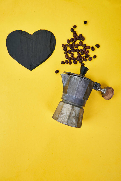 Vlakke lay-out van koffiezetapparaat en bonen op gele achtergrond. Koffie liefde concept. Moka koffiepot. Espresso maker. Proces van het maken van natuurlijke koffie van bonen. Bovenaanzicht. Kopieerruimte. - Foto, afbeelding