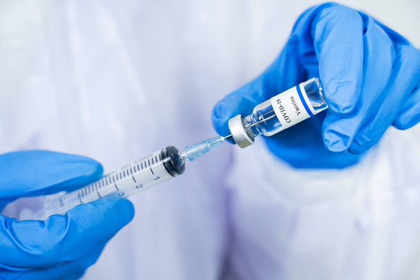 Lekarz, naukowiec, naukowiec w niebieskich rękawiczkach lub kombinezonie ochronnym przygotowującym do badań klinicznych szczepionki przeciw wirusowi koronawirusowemu covid-19 Koncepcja zagrożenia biologicznego - Zdjęcie, obraz