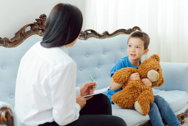 Picture of child psychologist working with young boy in office - Photo, image