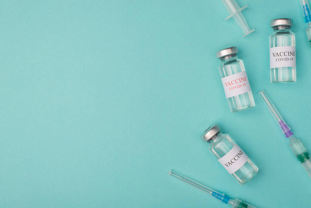 Medicare gyógyszer vizsga kísérlet koncepció. Felülnézeti kép a COVID-19 vakcinát tartalmazó injekciós üvegekről és a kék kékeszöld türkiz háttér fénymásoló felületén izolált felvételekről - Fotó, kép