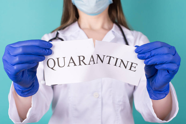 Quarantine is over free freedom people mask concept. Close-up cropped photo of female doctor in white lab coat gloves tearing quarantine paper text apart isolated on blue teal background - Foto, imagen