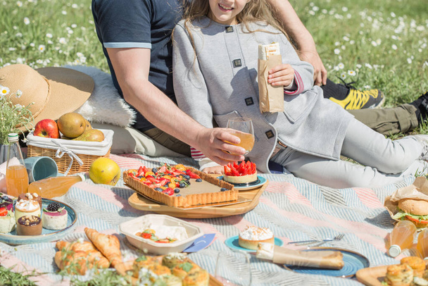  人々はチェックされたピクニックブランケットから食べ物を取ります。屋外夏の家族ピクニック - 写真・画像