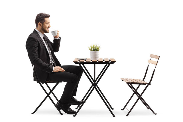 Geschäftsmann sitzt in einem Café und trinkt Espresso auf weißem Hintergrund - Foto, Bild