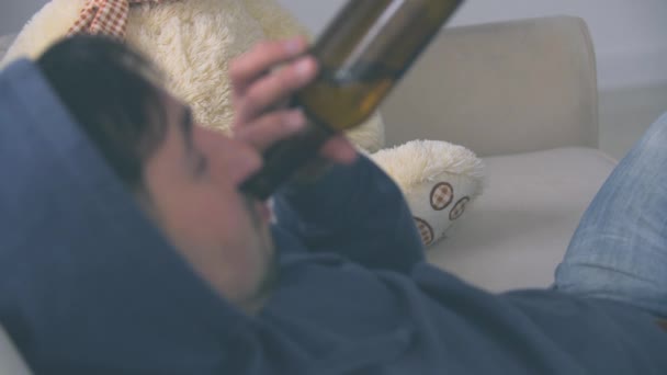 A man is drinking beer on a sofa at home in 4k slowmotion video. - Video, Çekim
