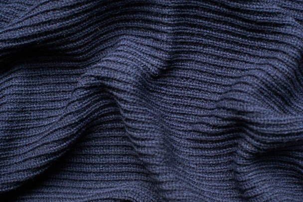 Pleats on fabric, knitted material of dark blue color, folds - Fotó, kép