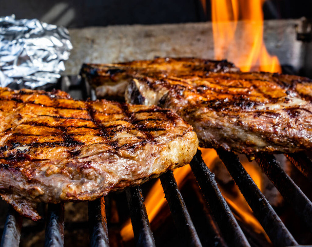Vuur likkend aan de steaks op de grill. Calgary, Alberta, Canada - Foto, afbeelding