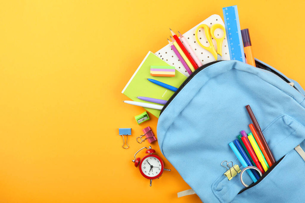Schulrucksack und Schulschreibwaren auf farbigem Hintergrund von oben. Konzept zurück zur Schule. - Foto, Bild
