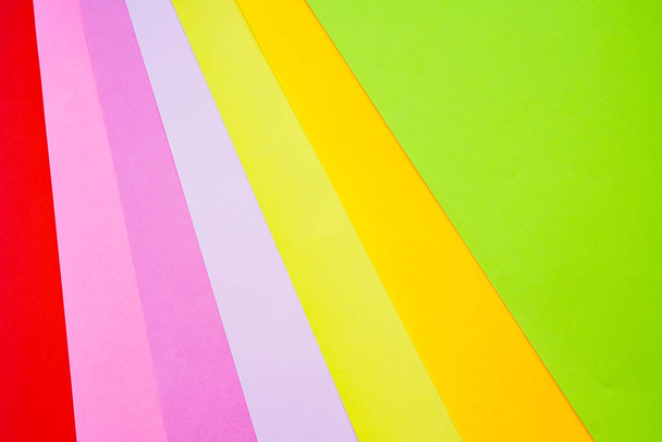 Φύλλα από φωτεινό χρωματιστό χαρτί γραφείου φωτογραφίζονται από πάνω γκρο πλαν σε λευκό φόντο. Κόκκινο, ροζ, μωβ, κίτρινο, πορτοκαλί, πράσινο - Φωτογραφία, εικόνα